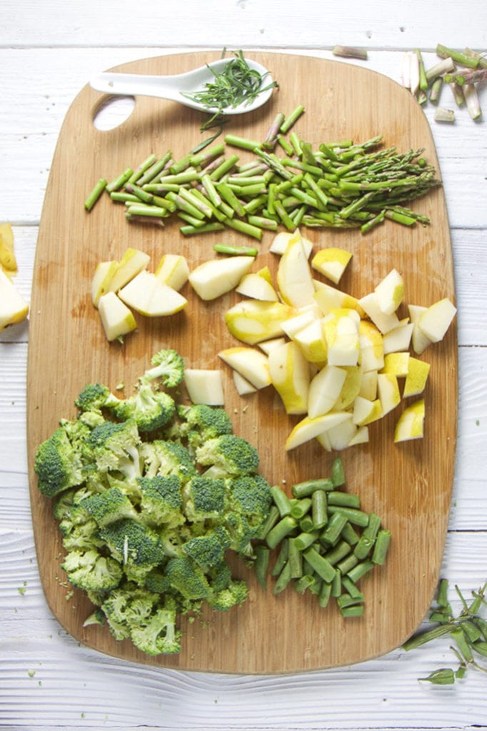 A cutting board and a spread of chopped veggies and fruit.