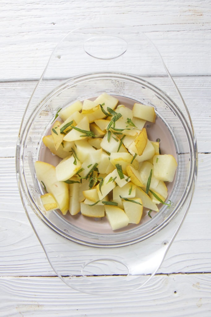 A steamer tray filled with pears and tarragon.