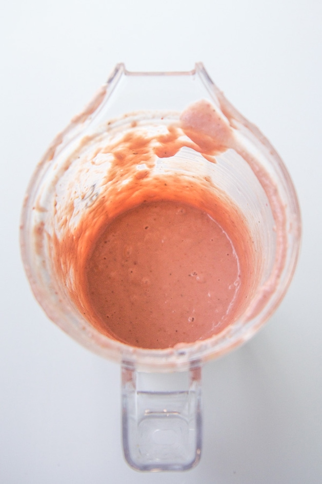 A blender full of strawberry salmon baby food puree.