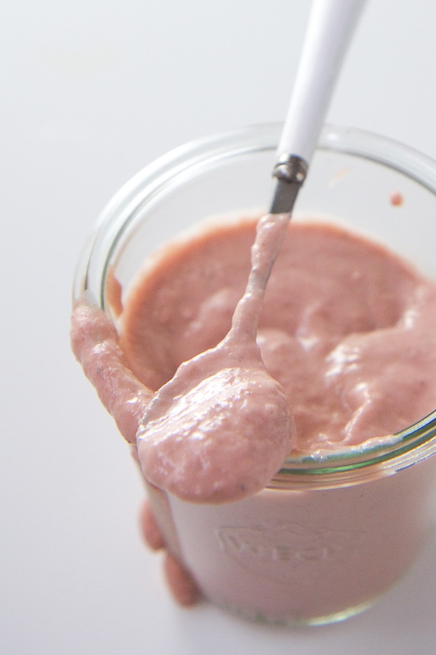 Glass Jar filled with a thick baby food puree featuring strawberries and salmon.