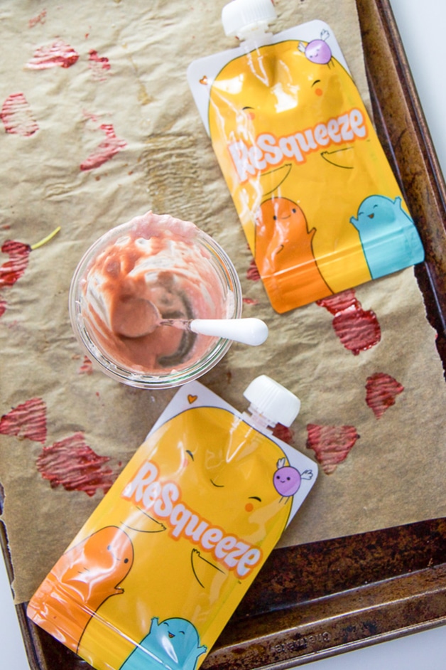 A baking try with a clean glass jar of baby food and 2 reusable baby food pouches.
