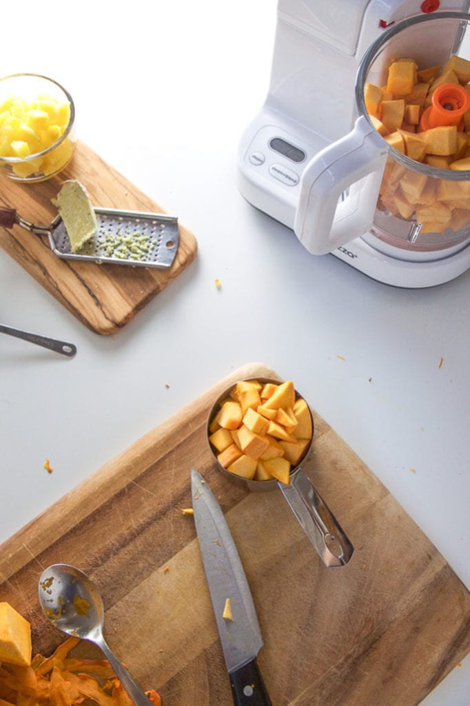 spread of cutting boards with fresh produce with a baby food making machine in the corner.