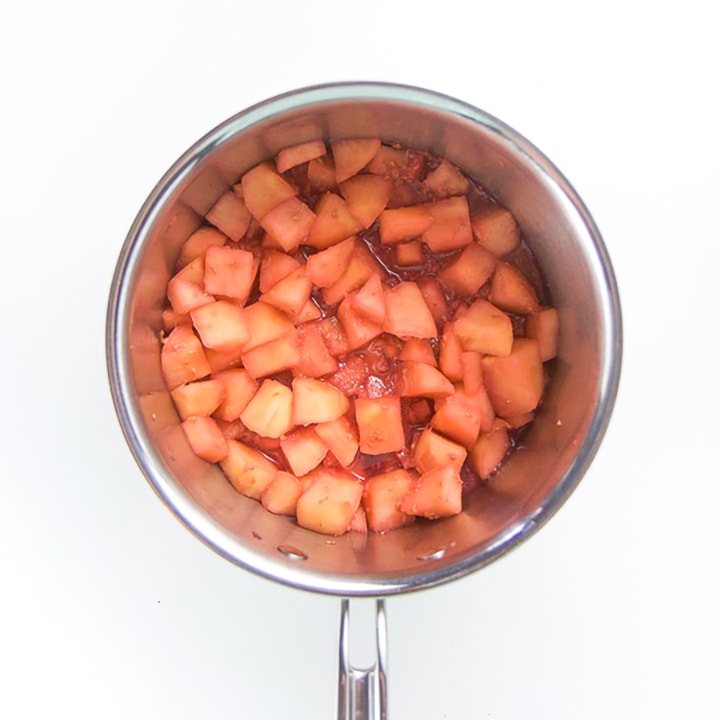 Saucepan full of cooked apples and raspberries.