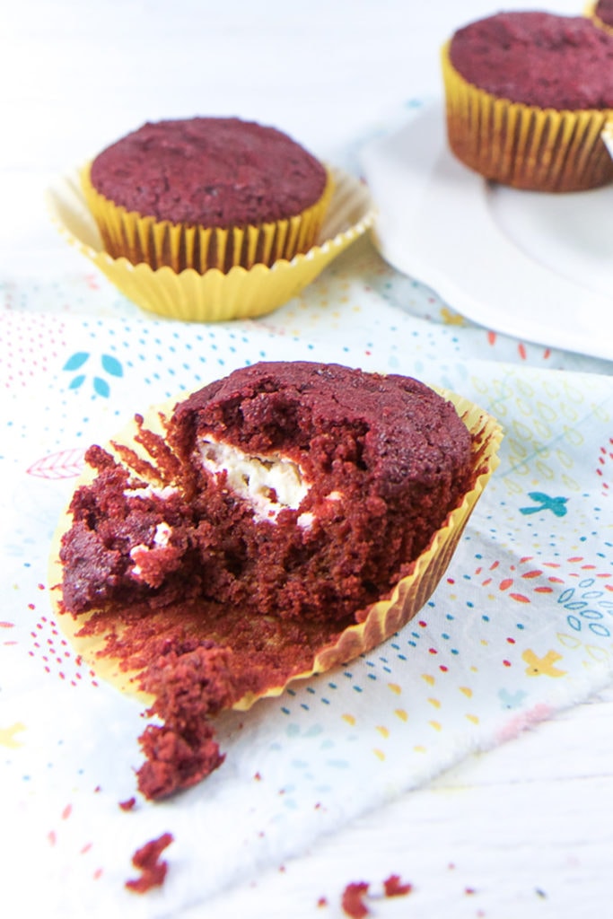 Beet muffin half way unwrapped sitting on a napkin.