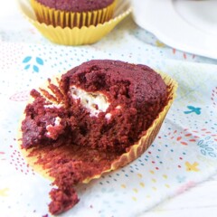 Beet muffin half way unwrapped sitting on a napkin.