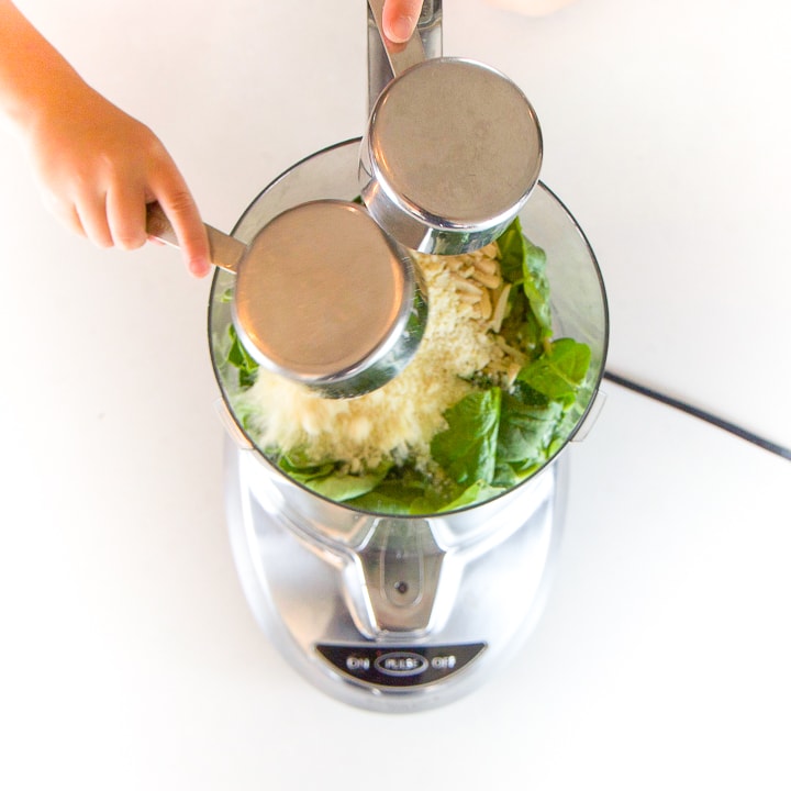 2 hands dumping food into a food processor.