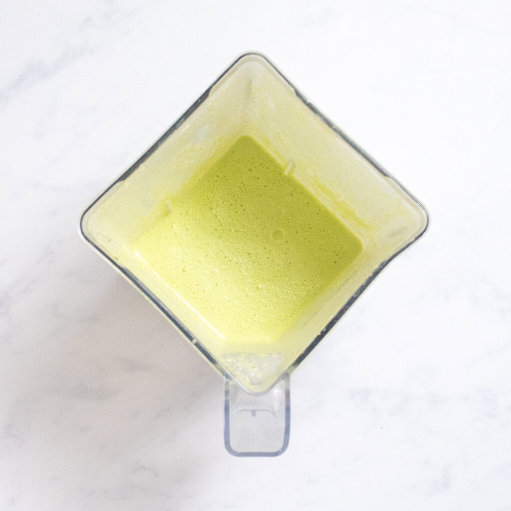 Blender on my white marble kitchen counter with the blended spinach mixture for the waffles.