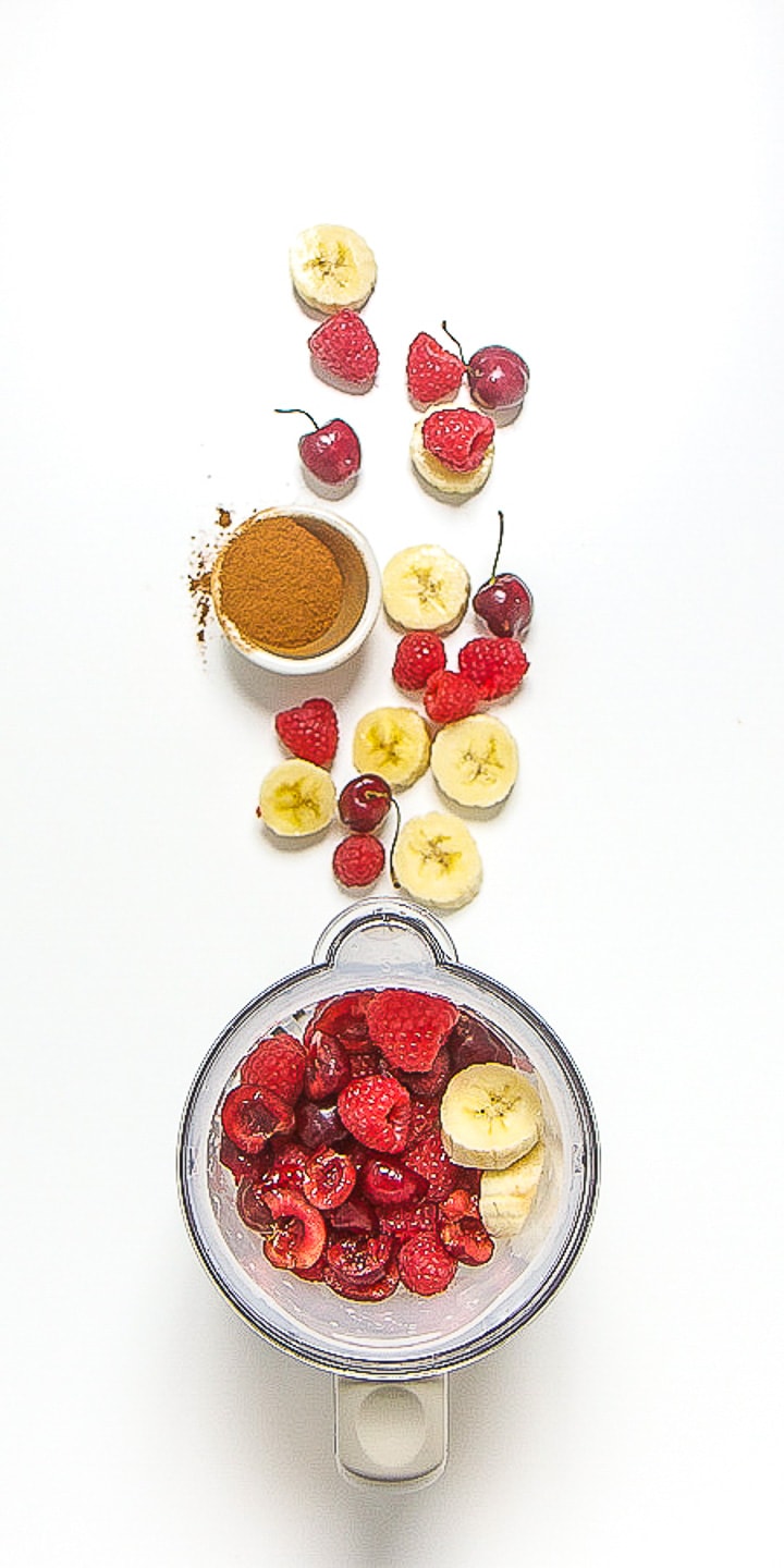 image is of a blender with produce scattered outside of it