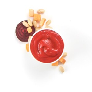 Small white bowl filled with homemade baby food puree surrounded by produce.