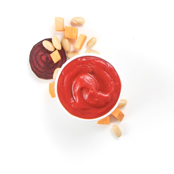 Small white bowl filled with homemade baby food puree surrounded by produce.