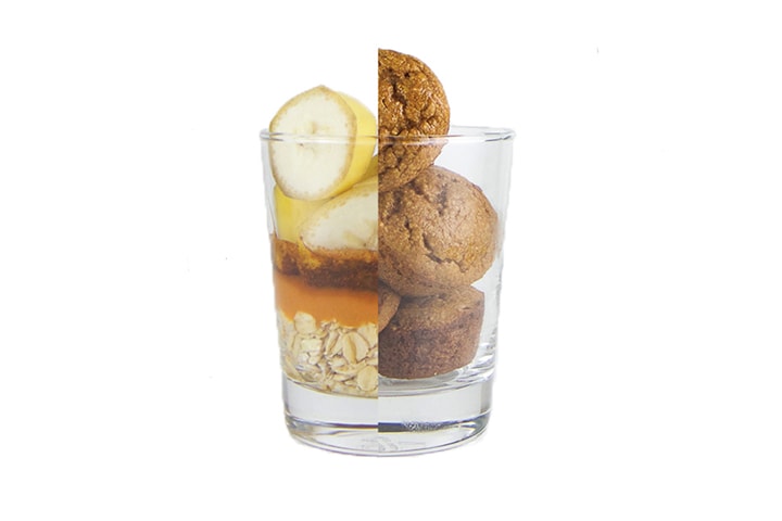 Class cup cut in half with half of it the ingredients in the muffins, the other half of the cup is the muffins themselves.