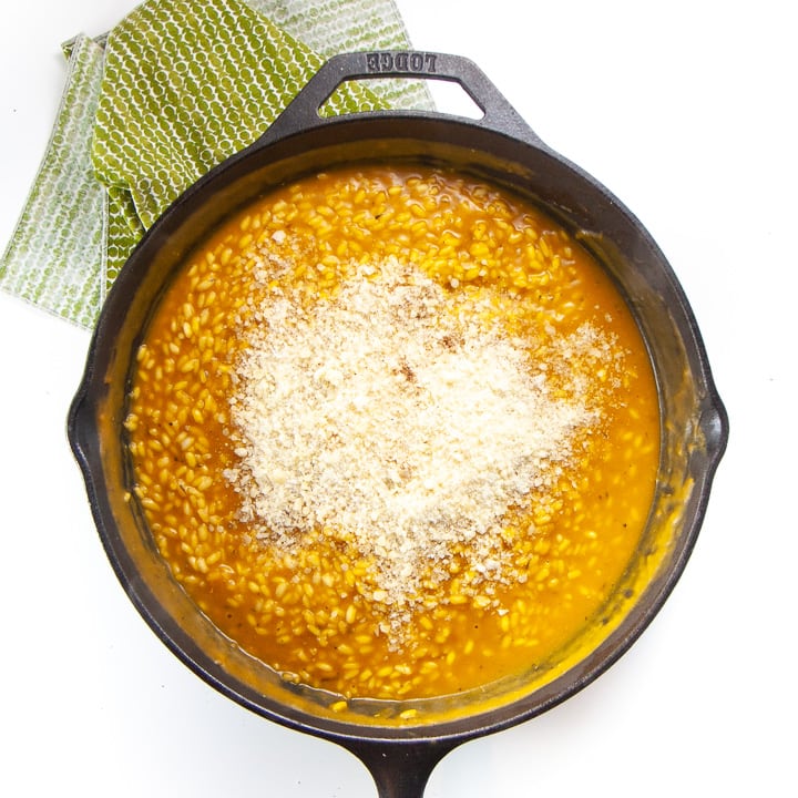 Kid friendly pumpkin risotto in a cast iron skillet - cooked with parmesan on top.