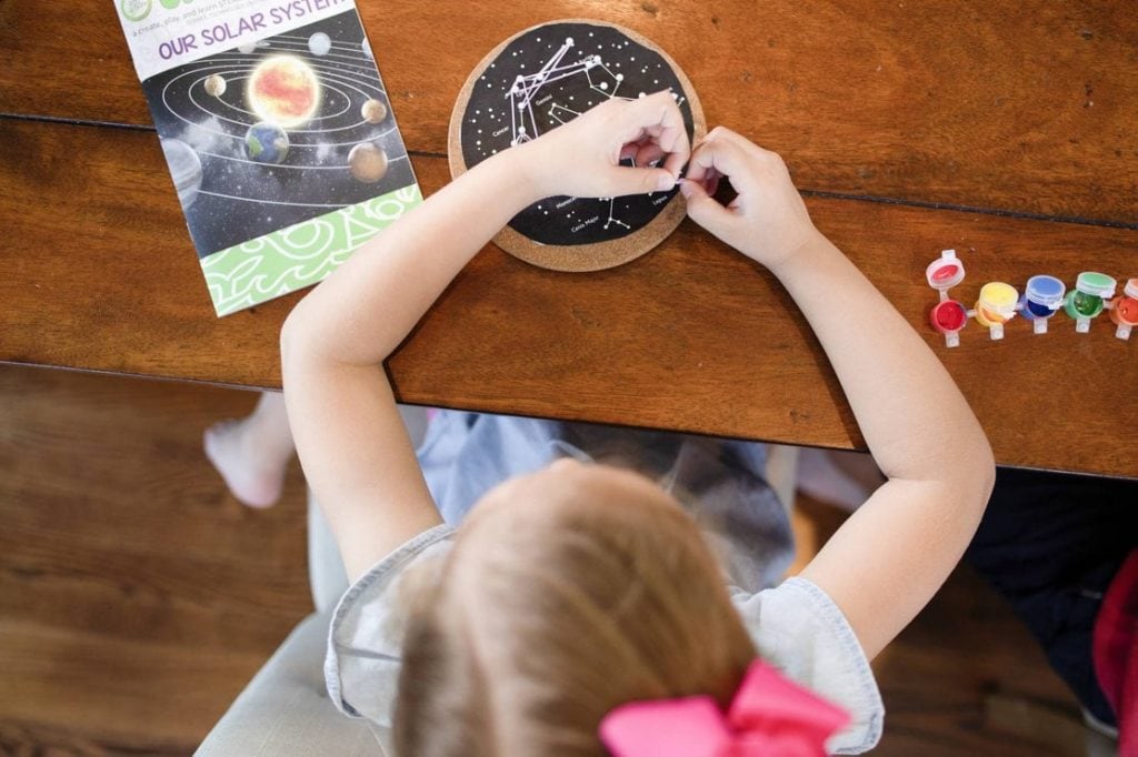 Small kid working on a craft project from a subscription box.