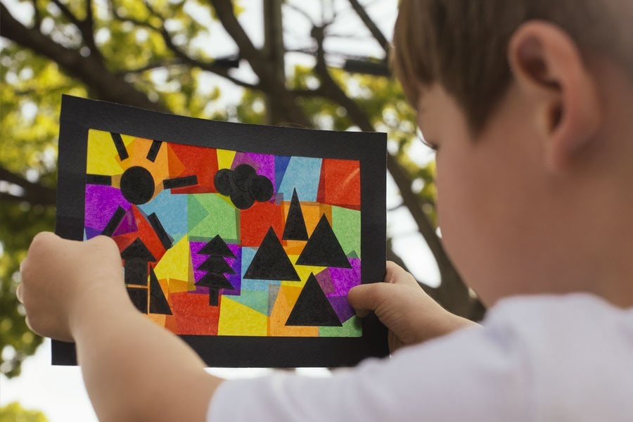 Kid holding up a colorful collage.