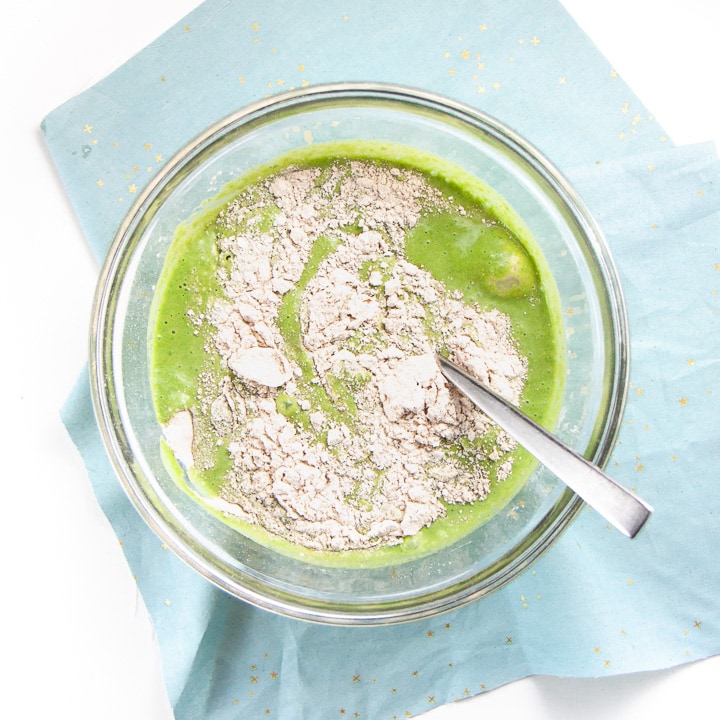 green wet ingredients halfway mixed together with the flour.