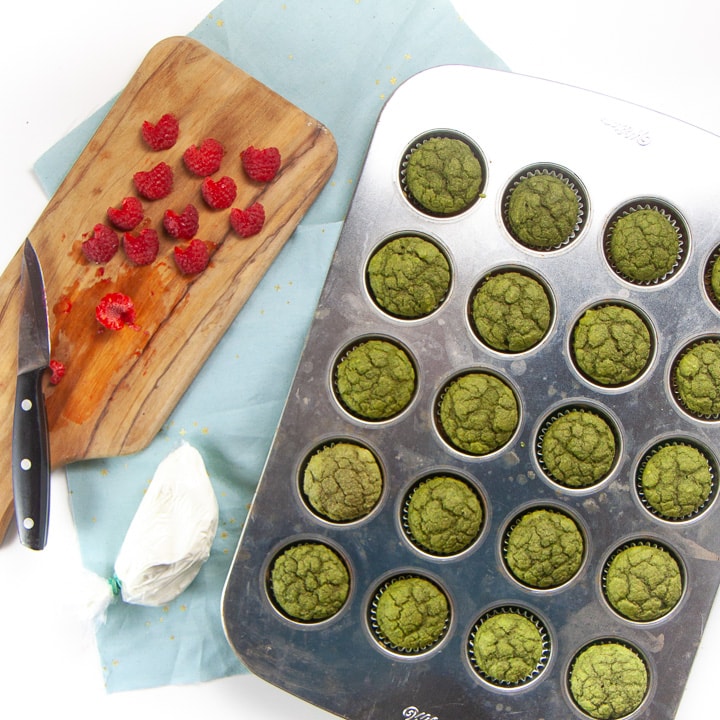 Cooked grinch muffins with a cutting board full of raspberry hearts.