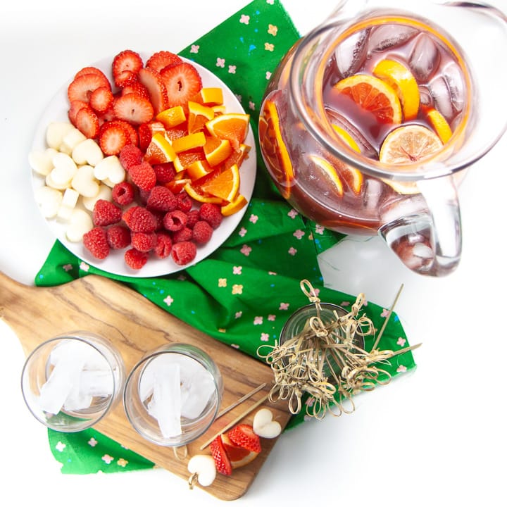 Spread of pitcher with Christmas punch and a plate with fruit and sticks for kids to make them.