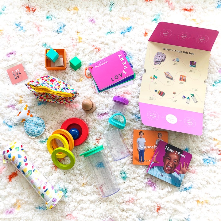 colorful baby toys scattered on a white and dotted carpet.