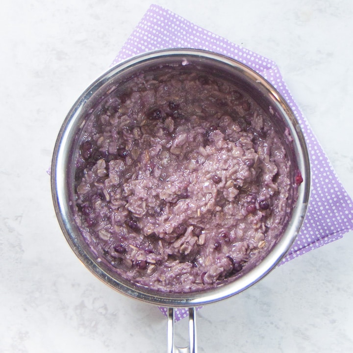 Saucepan filled with cooked oats and blueberries.