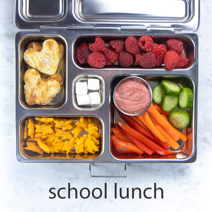 metal school lunch box full of beet hummus, dippers and other snacks.