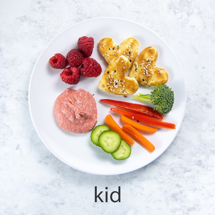 white round kid plate full of beet hummus and dippers.