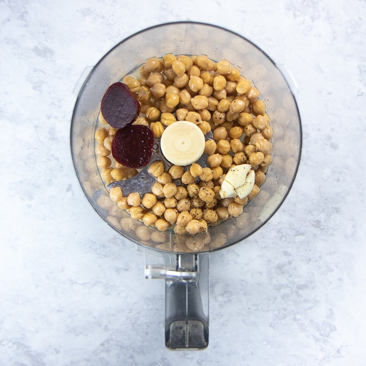 food processor filled with ingredients to make beet hummus