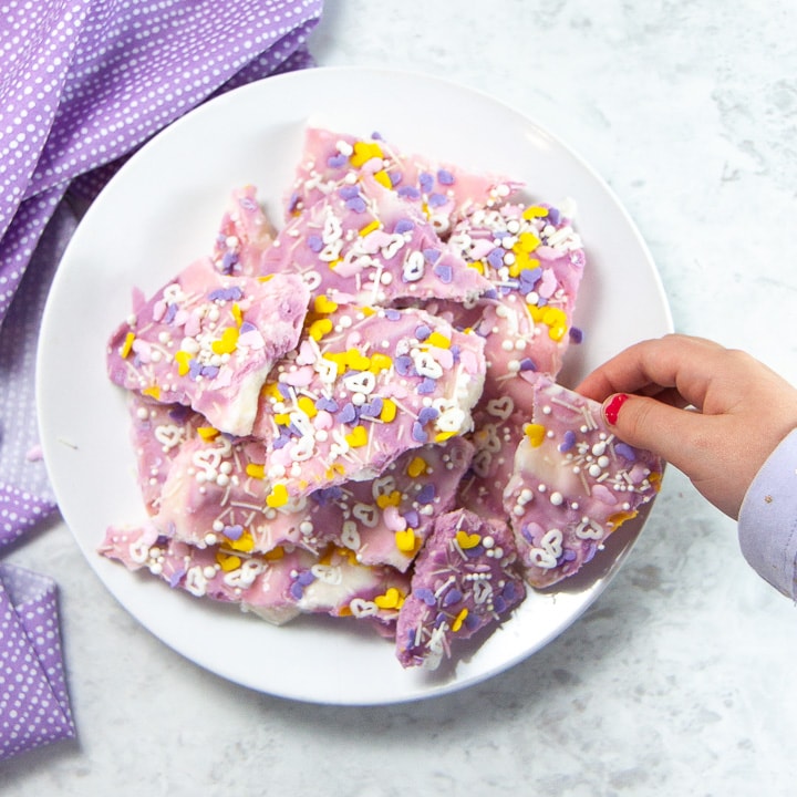 Kid hand reaching for frozen unicorn bark.