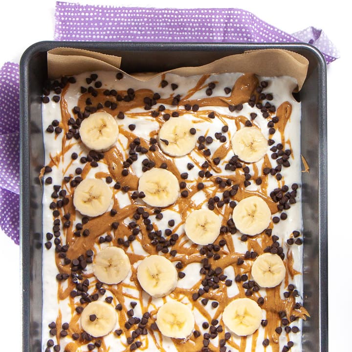 A baking dish of banana, peanut butter and chocolate frozen yogurt bark for toddlers and kids.