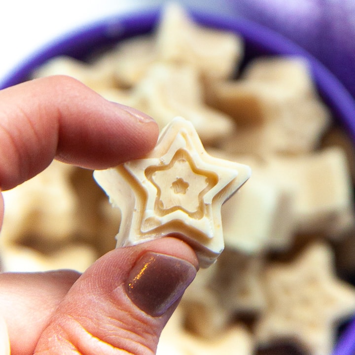 Fingers holding up a star shaped melts for baby.