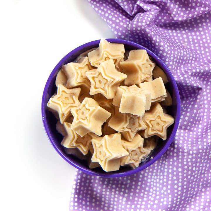 A purple bowl filled with star shaped peanut butter banana melts for baby.