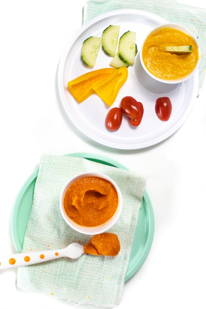 Two different plates with recipe on them - one is a veggie loaded dip for toddler and the other is a small bowl of veggie loaded puree for baby.