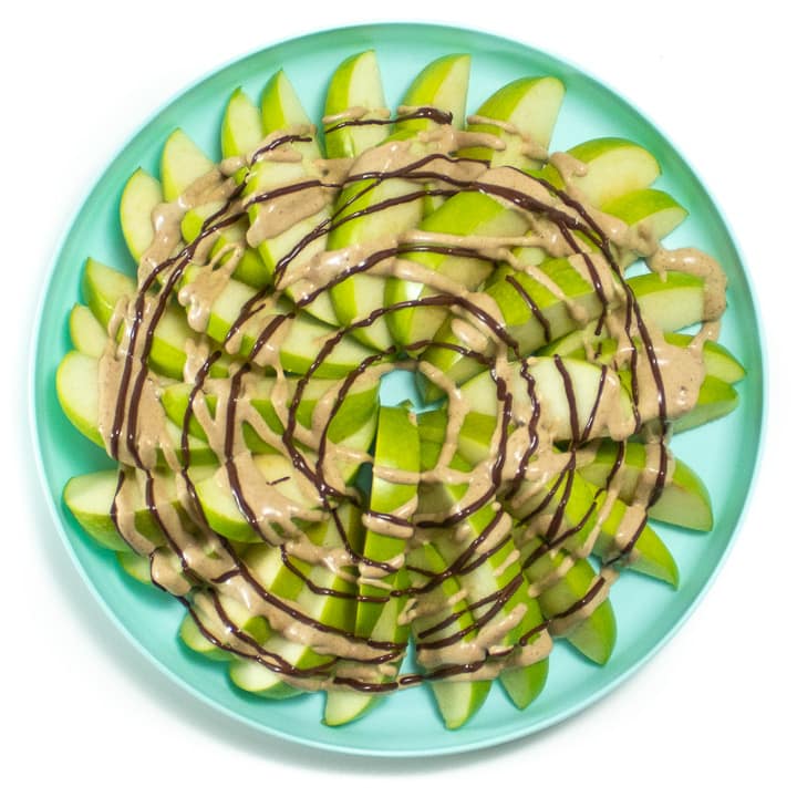 Plate of apple slices with a healthy caramel sauce and melted chocolate onto.