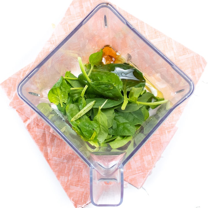 Blender with spinach and yogurt bark ingredients inside.