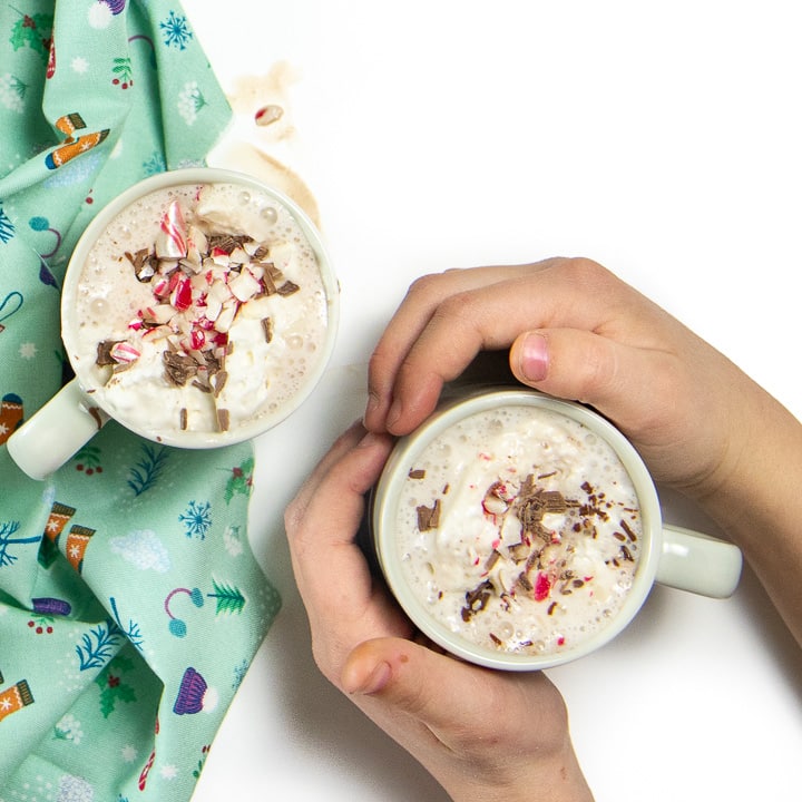 Small hands holding a mug of hot chocolate with toppings!