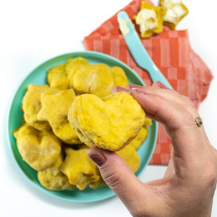 Hand holding a close up of a heart shaped pumpkin biscuit.