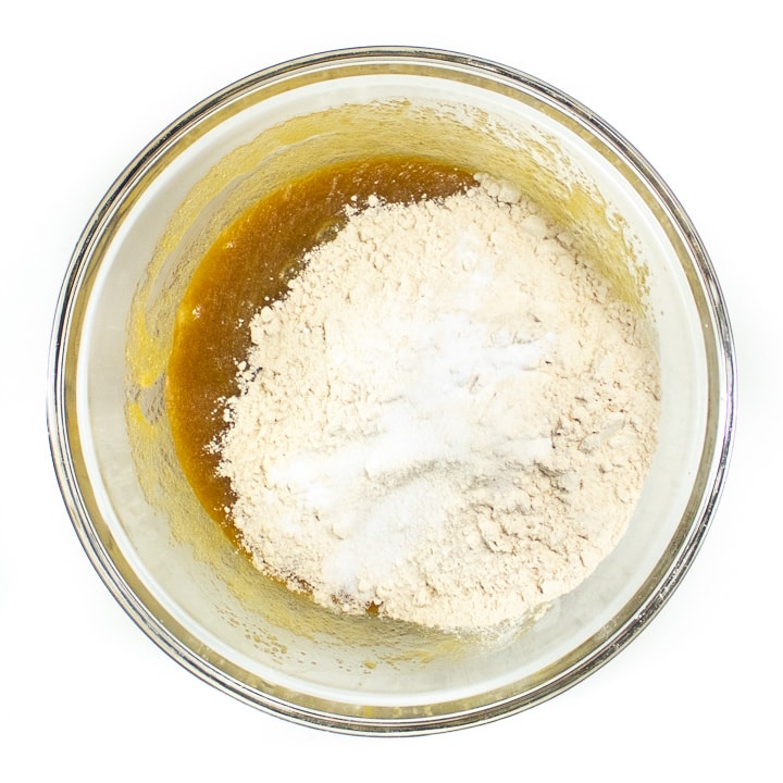 Bowl with wet ingredients and whole wheat flour ready to mix together.
