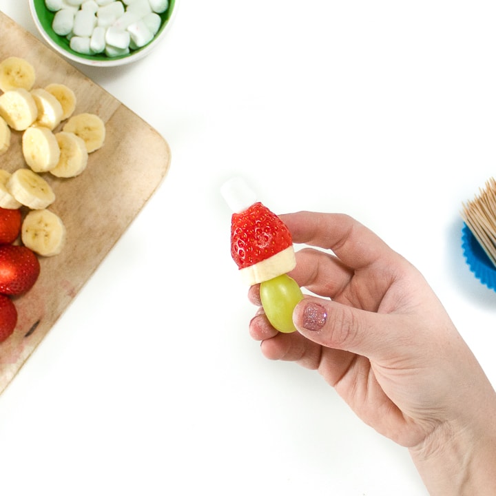Hand holding a fruit kabob.