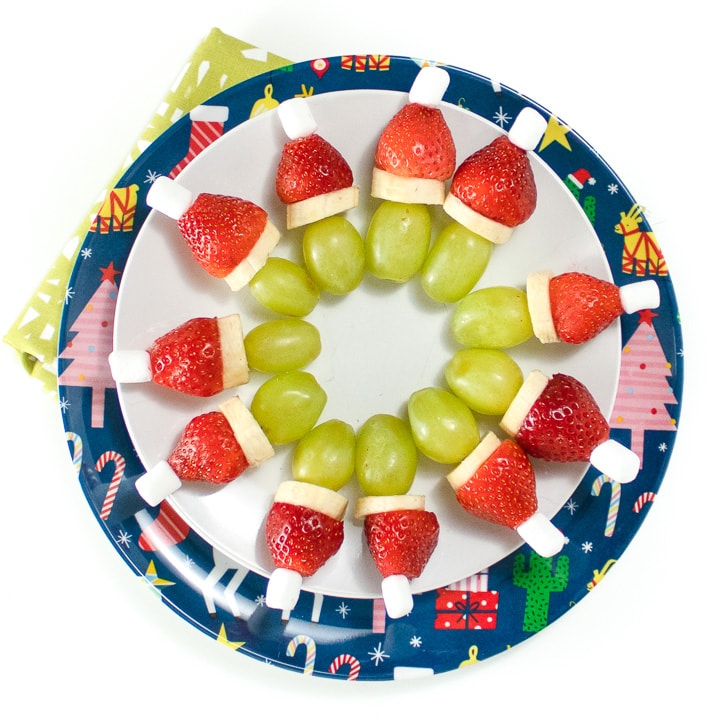 2 round plates with a circle of grinch kabobs on it.