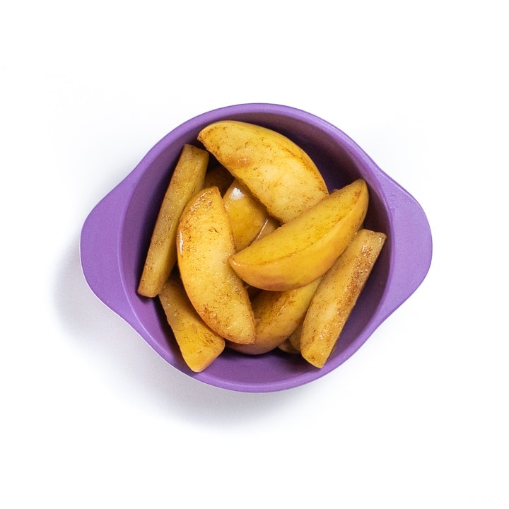 Purple small baby bowl filled with soft apples for baby.