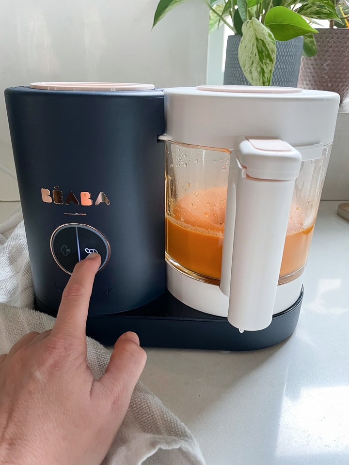 Hand hitting the blend button on a black Beaba babycook.