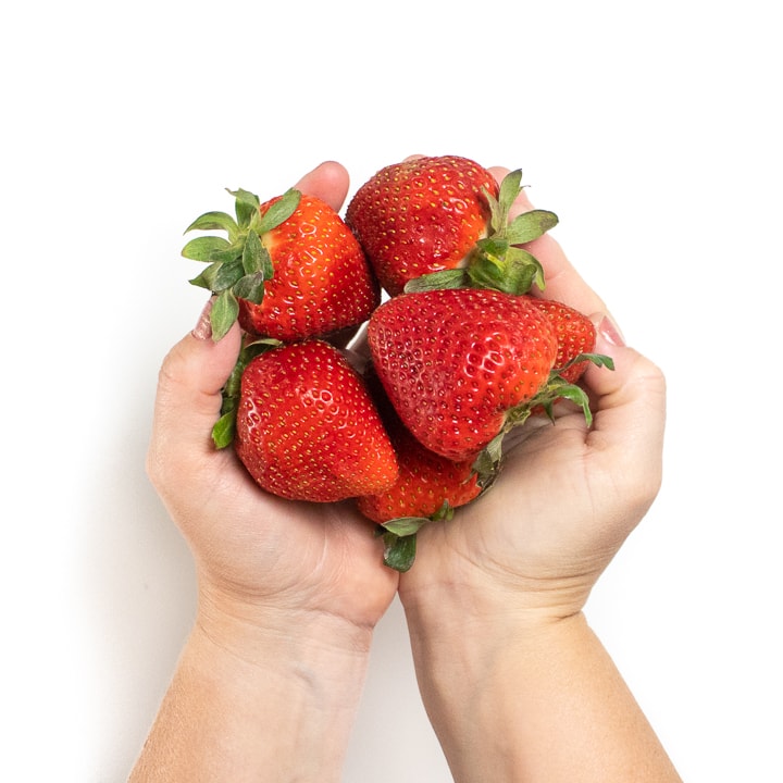 Hands holding fresh strawberries.