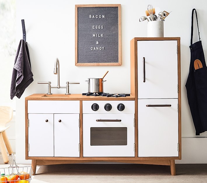 White and wood mid century style play kitchen in a fun kids room.
