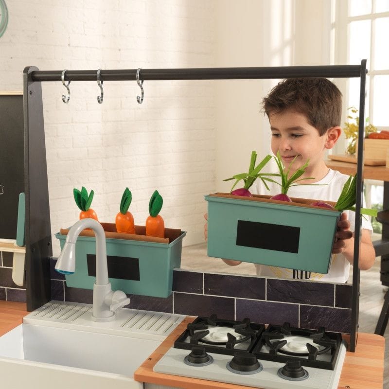 Boy moving around his play kitchens garden boxes.