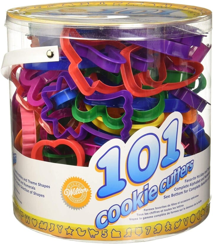 round plastic container with a ton of brighly colored cookie cutters for kids.