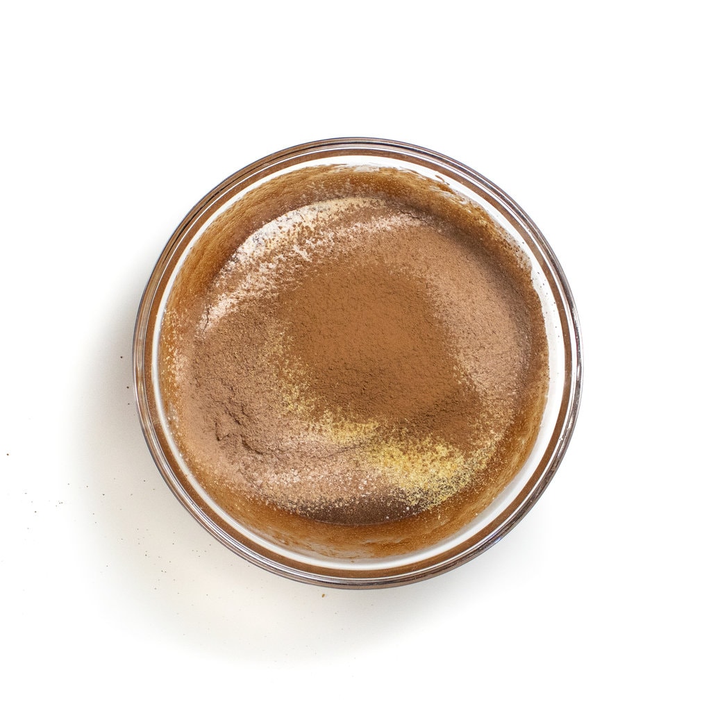 A bowl of brownies with the wet ingredients on the bottom and dry ingredients on top about to get mixed.