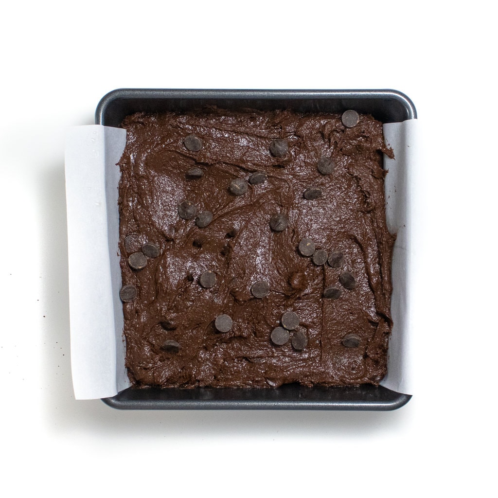 And uncooked tray of brownies ready to be baked with chocolate chips on top.