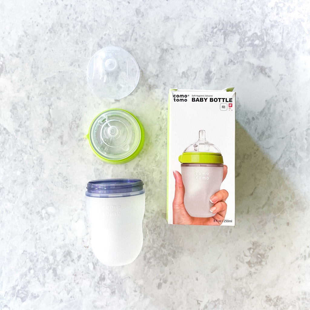 Image of a Comotomo box with a bottle taken apart against a marble countertop.
