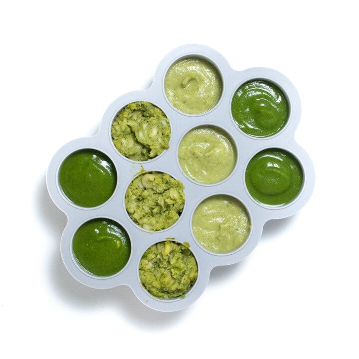 Gray freezer tray with 4 different kinds of zucchini purees for baby ready to be frozen.