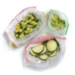 Three Ziploc bags full of frozen zucchini three different ways.