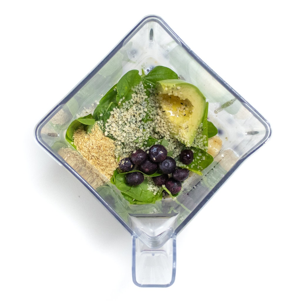 Blender sitting on a white background with ingredients for a pregnancy smoothie inside.